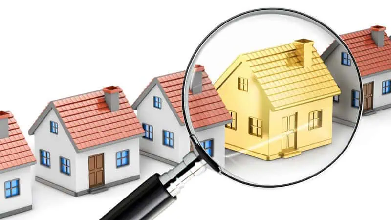 Magnifying glass searching houses to find the gold house