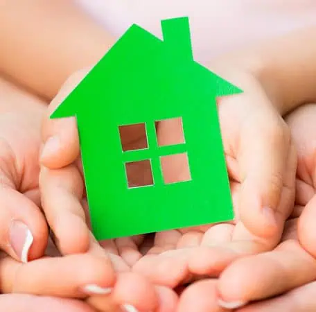 Multiple hands holding a green house.