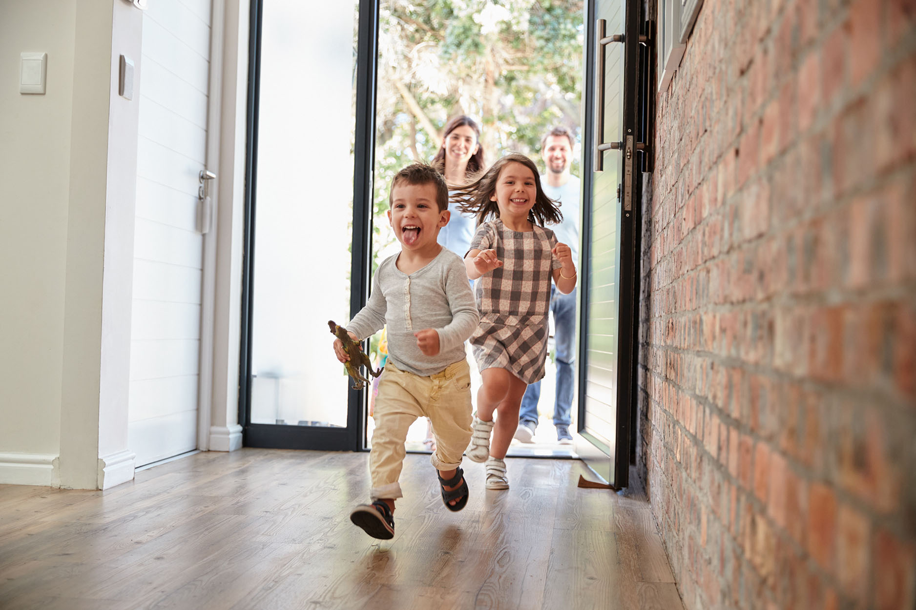 Two young children and their parents entering the front door of their new family home purchased in Brisbane with a Templeton Buyer's Agent