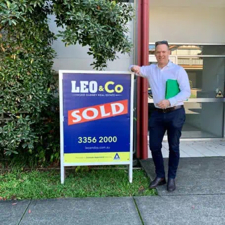 Brisbane Buyers Agent Sam Price standing next to a sold sign at Alderley.