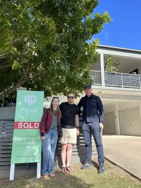 Buyers agent Sam Price with clients standing outside three new home. 