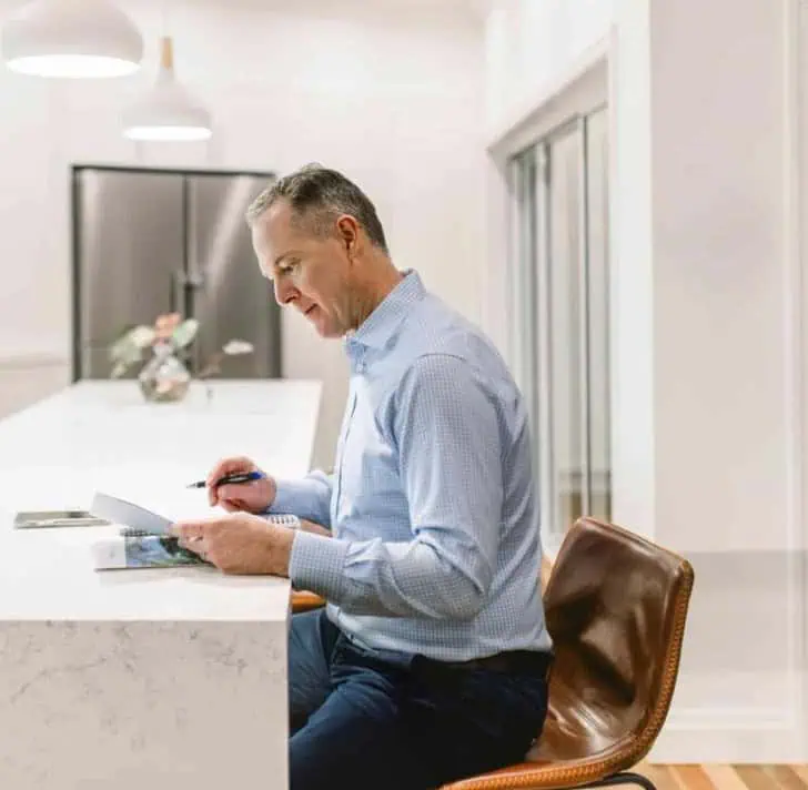 Sam Price, Brisbane Buyer's Agent, reviewing property plans at a kitchen bench